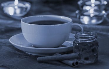 A cup of tea on a table with candles